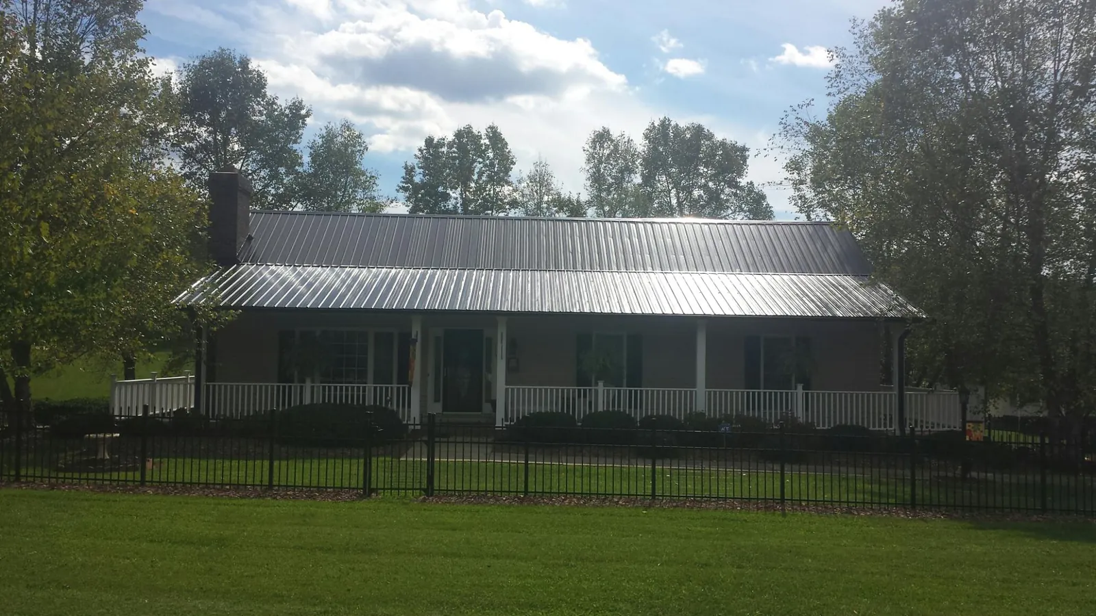 Gray metal roof on a brick ranch with a full width front porch — Gutter Guard Installation work by our crew in Beachwood